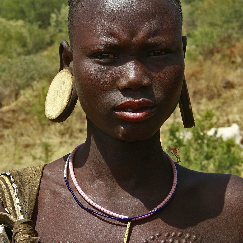 Mursi tribe woman with traditional lip plate in Ethiopia Hamar tribe cultural dance in Southern Ethiopia Scenic landscape of the Omo Valley region Traditional tribal market in Jinka Ethiopia Karo tribe body painting near the Omo River Travelers enjoying the 7-Day Omo Valley Tour in Ethiopia